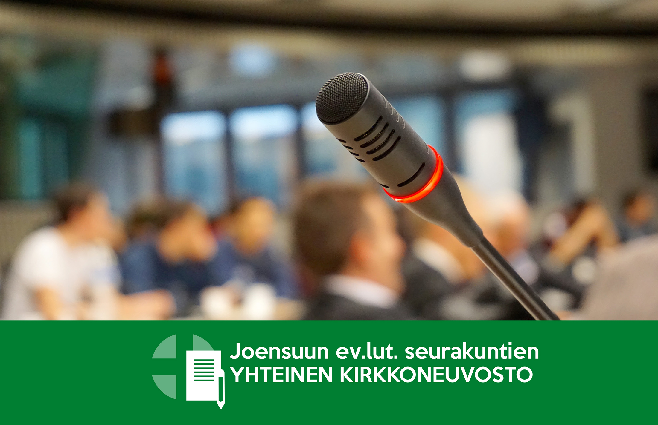 kuvassa etualalla mikrofoni, taustalla ihmisiä, tekstinä Joensuun ev.lut. seurakuntien yhteinen kirkkoneuvosto