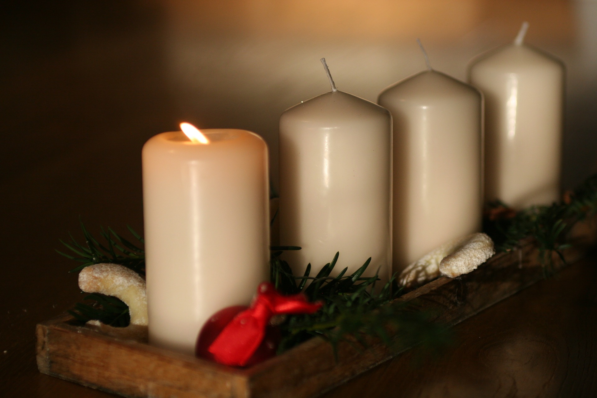Kuvassa on rivissä neljä kynttilää, joista vasemmanpuolimmaisin palaa.