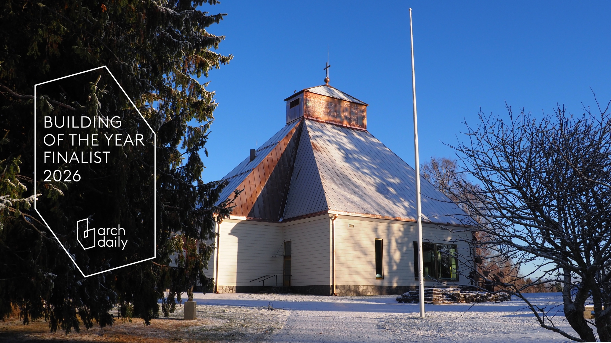 Kiihtelysvaaran kirkossa on vaaleat hirsiseinät ja kuparinen katto. Kirkon vieressä on kuusi, jonka päällä ...