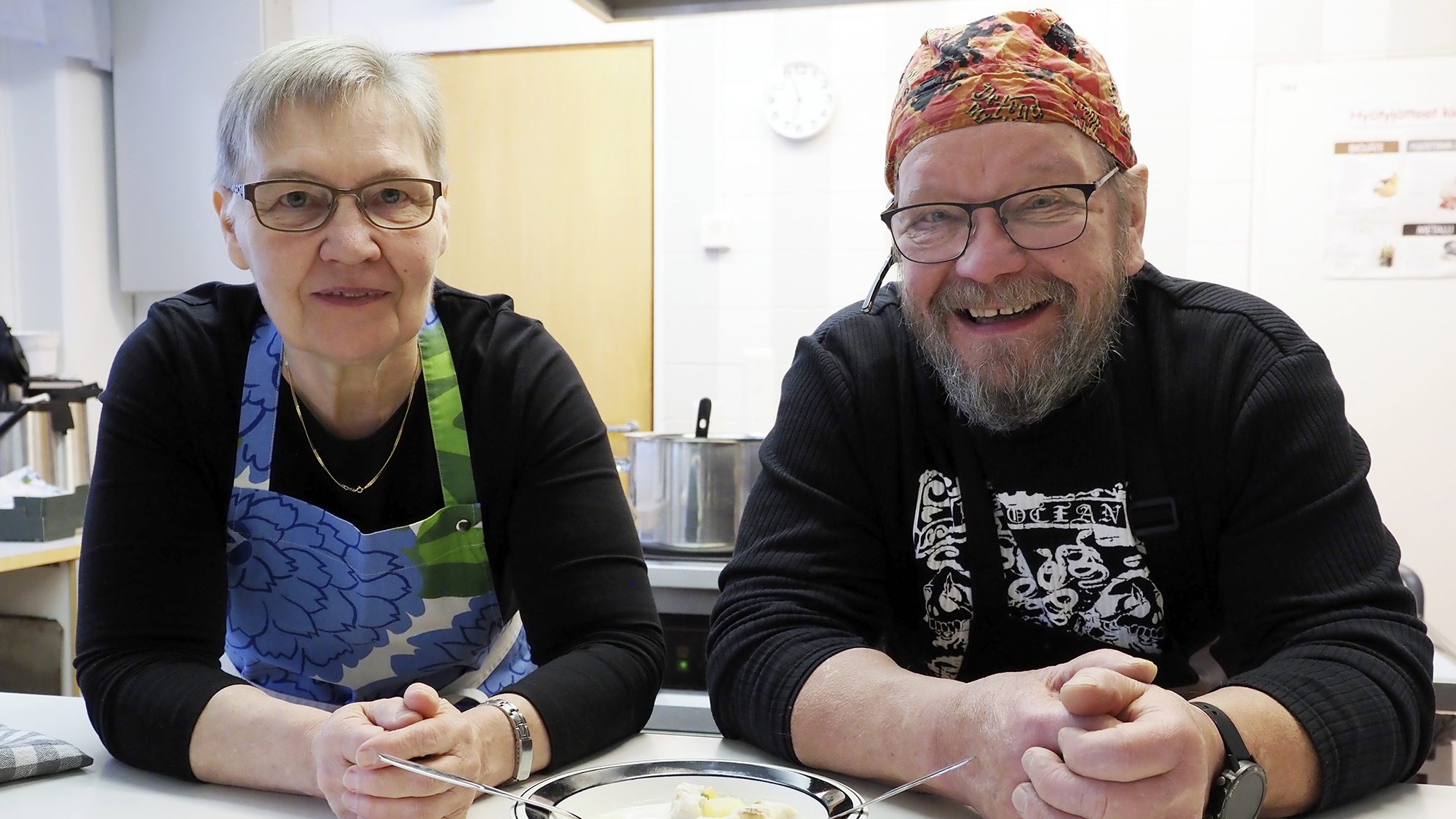 Aino Kakkonen ja Hannu Soikkeli ovat pöydän äärellä. Pöydällä on kalakeittolautanen.