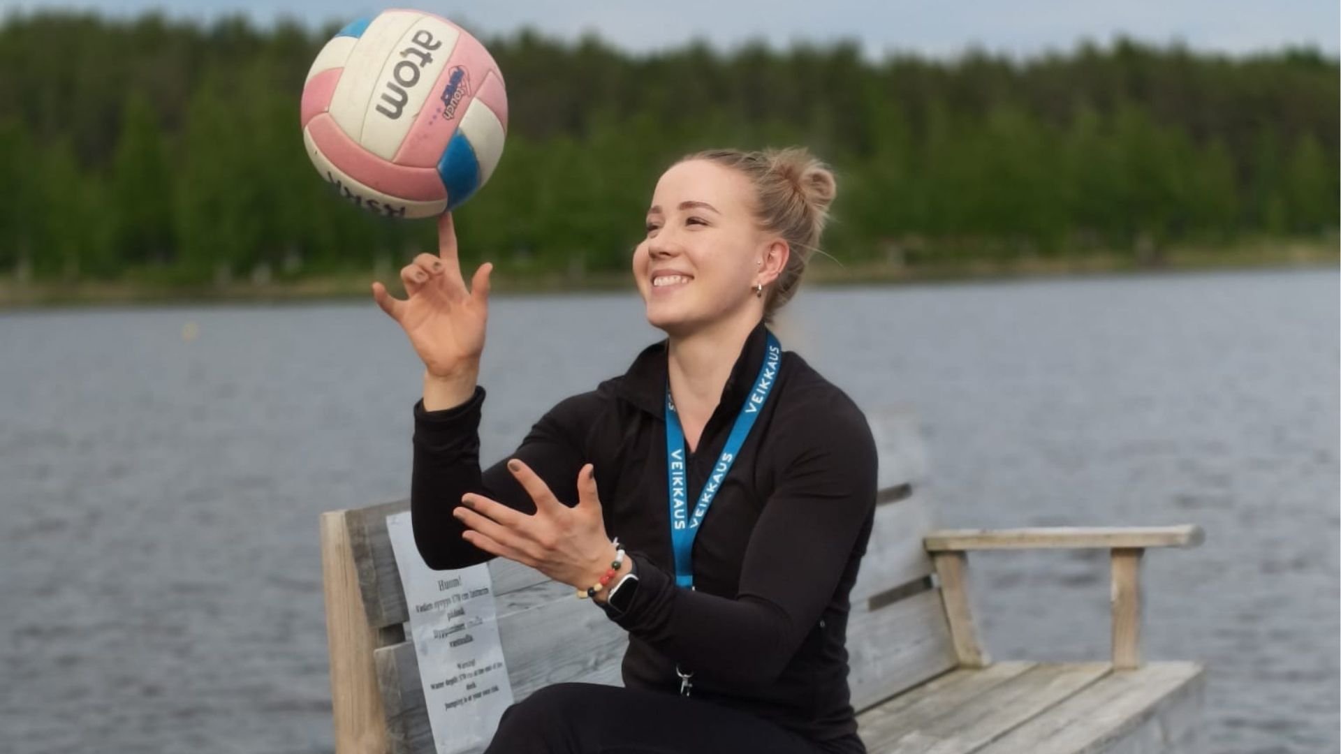 Siiri Nyyssönen istuu laiturilla ja pyörittää lentopalloa sormen päässään.