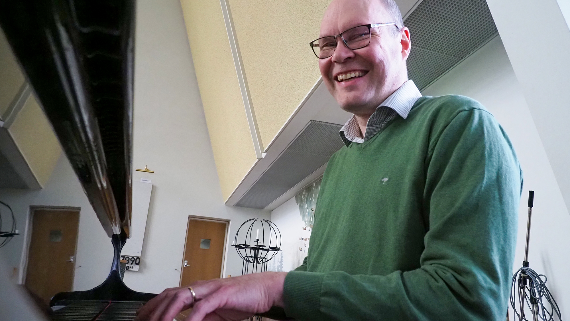 Mikko Juntusen sormet ovat flyygelin koskettimilla, ja hän hymyilee.