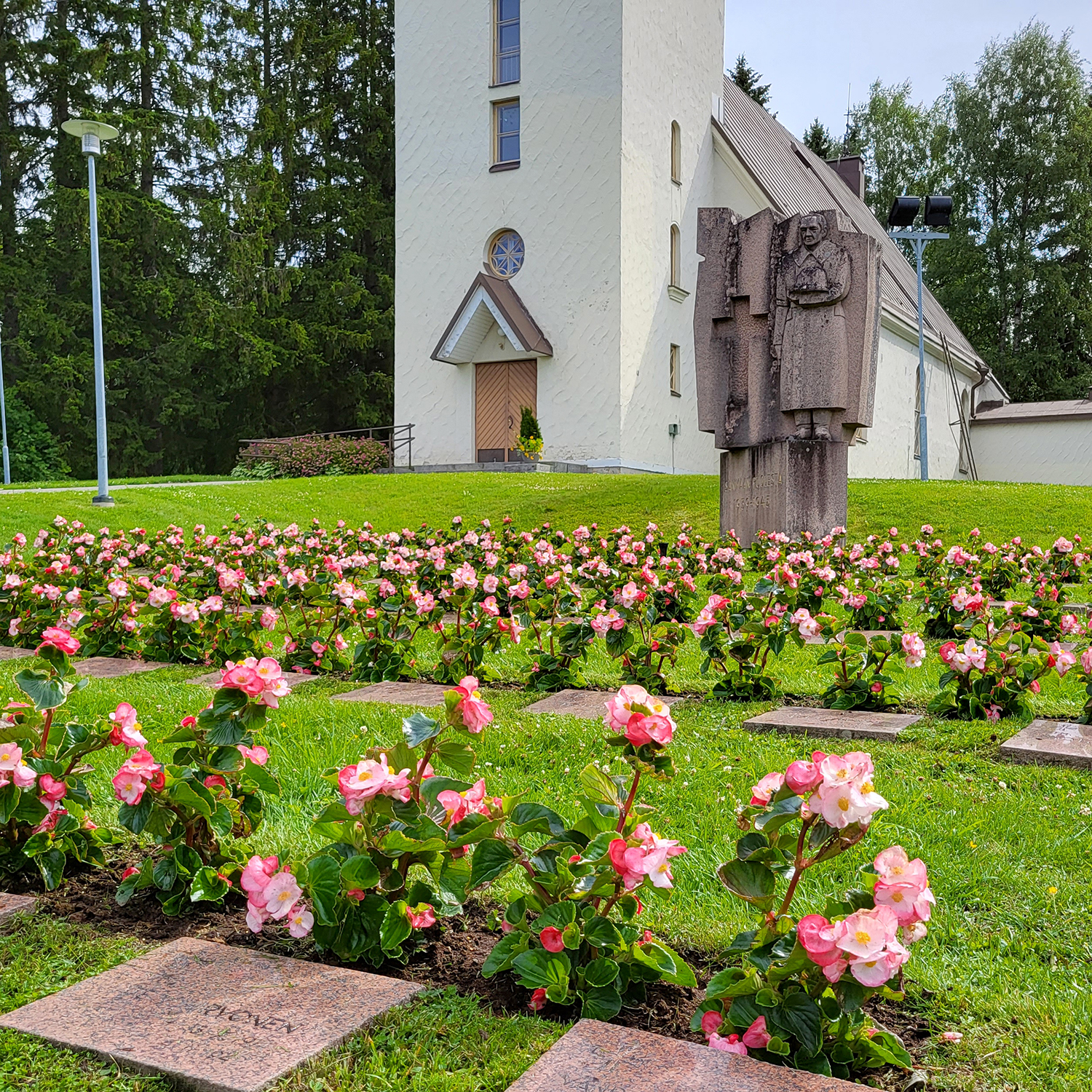 Hauta-alue ja muistomerkit nurmialueella kirkon edessä.