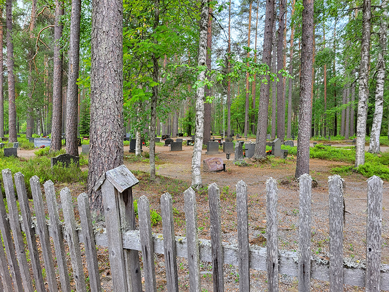 Puuaita, jonka takana metsäinen hautausmaa.