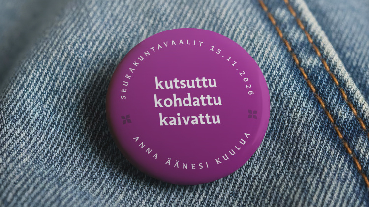 Lila rintanappi farkkukankaassa, tekstinä kutsuttu, kohdattu, kaivattu