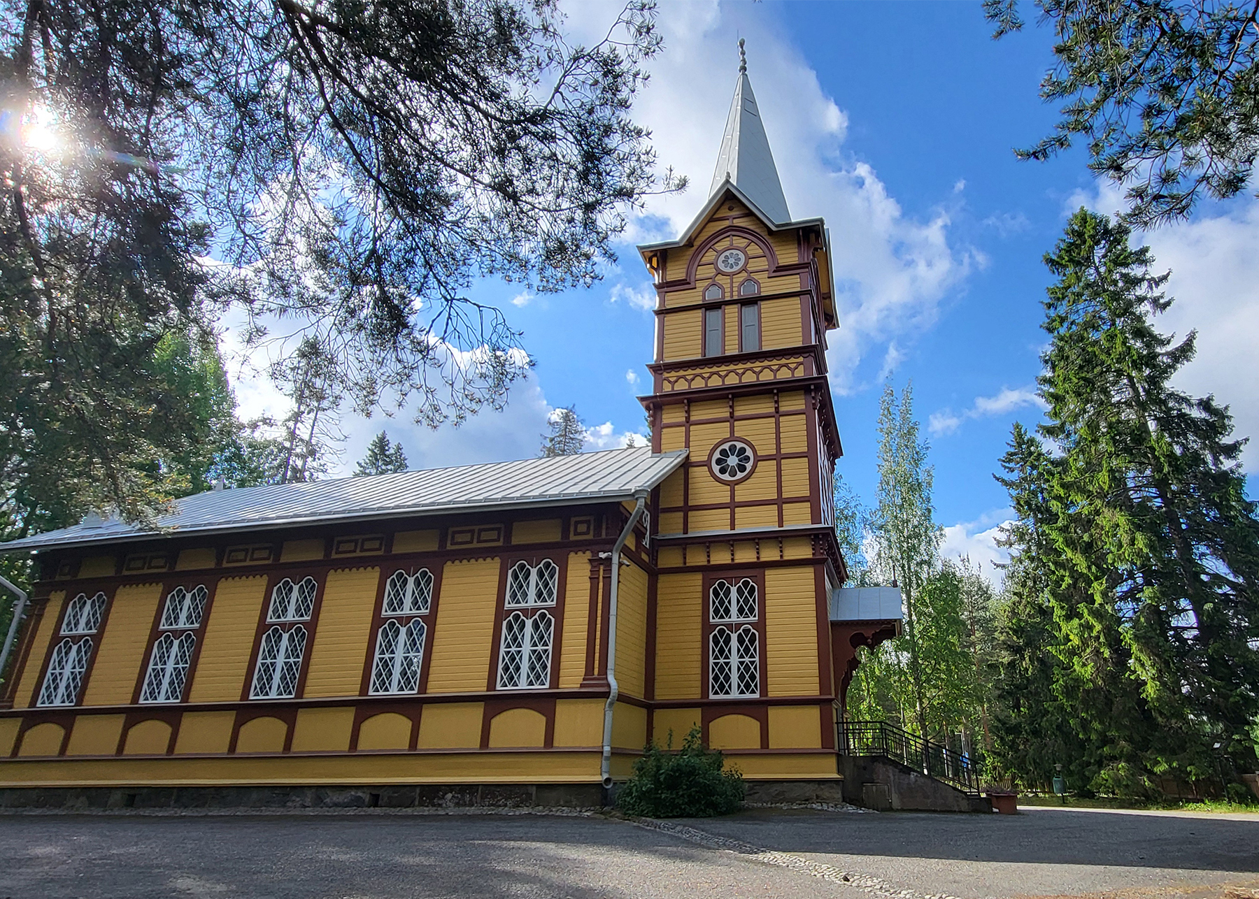 Utran kirkko Kelta-ruskea vanha puukirkko, etuosassa torni, koristeelliset ikkunat.