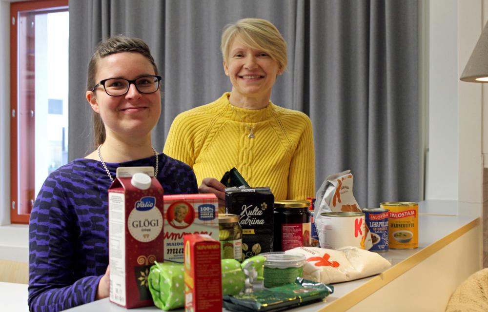 Diakoniatyöntekijät Pauliina Martikainen ja Marja Ikonen seisovat pöytätason takana. Päydälle on purettu yh...