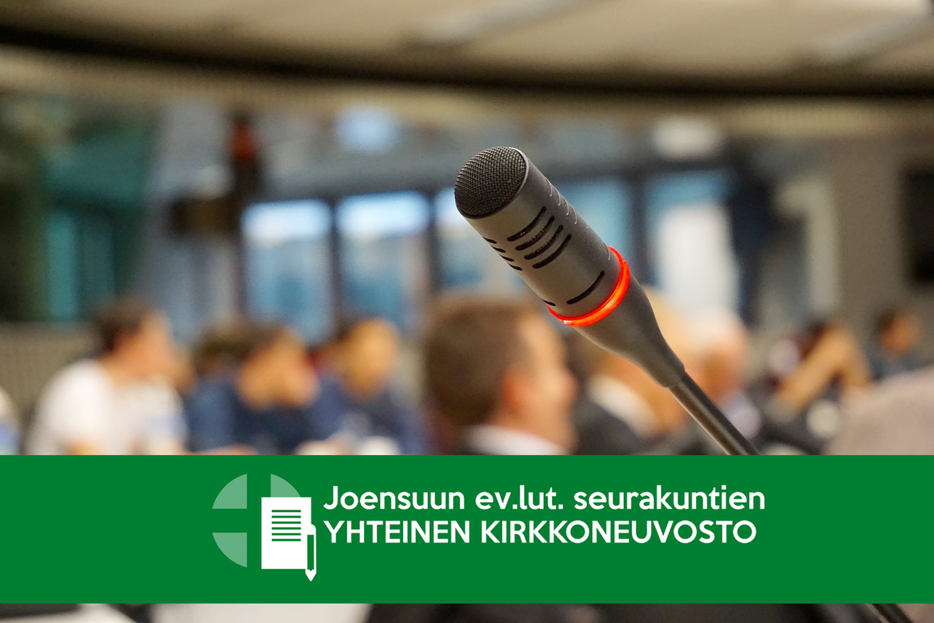 mikrofoni etualalla, takana ihmisiä, kuvan päällä teksti Joensuun ev.lut. seurakuntien yhteinen kirkkoneuvosto