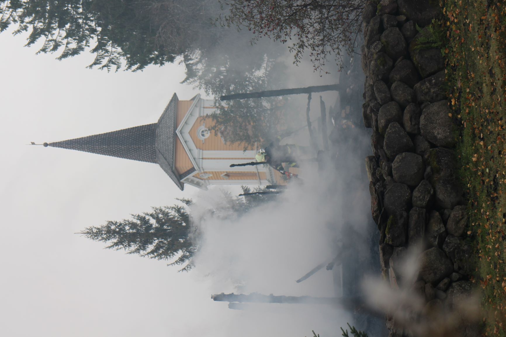 Tulipalossa säästynyt kellotapuli näkyy kirkon savuavien raunioiden takana.